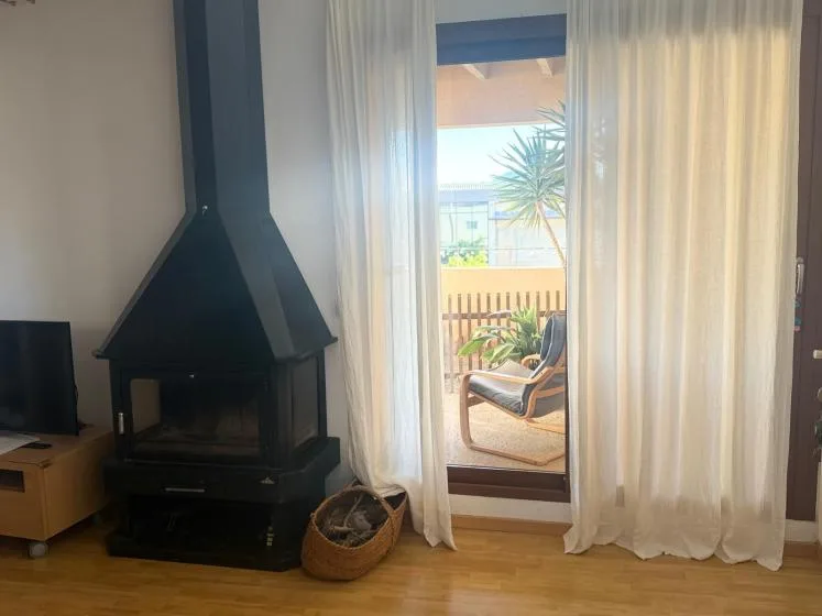 A living room with a dark fireplace and a glass door opening onto a balcony.