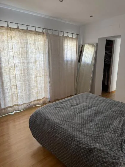 Un dormitorio con una cama junto a grandes ventanas con cortinas.