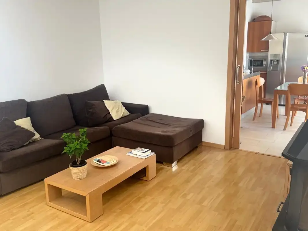 Una sala de estar con asientos oscuros y una mesa de centro de madera.