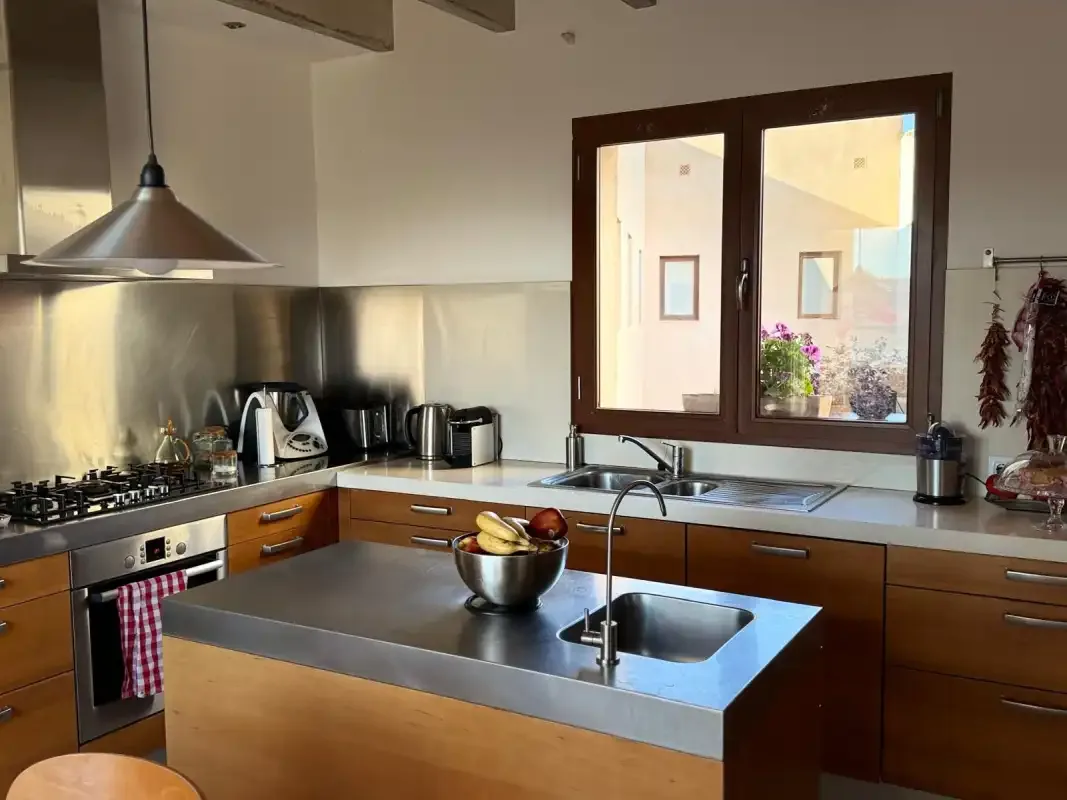 Una cocina moderna con una isla central y una ventana sobre el fregadero.
