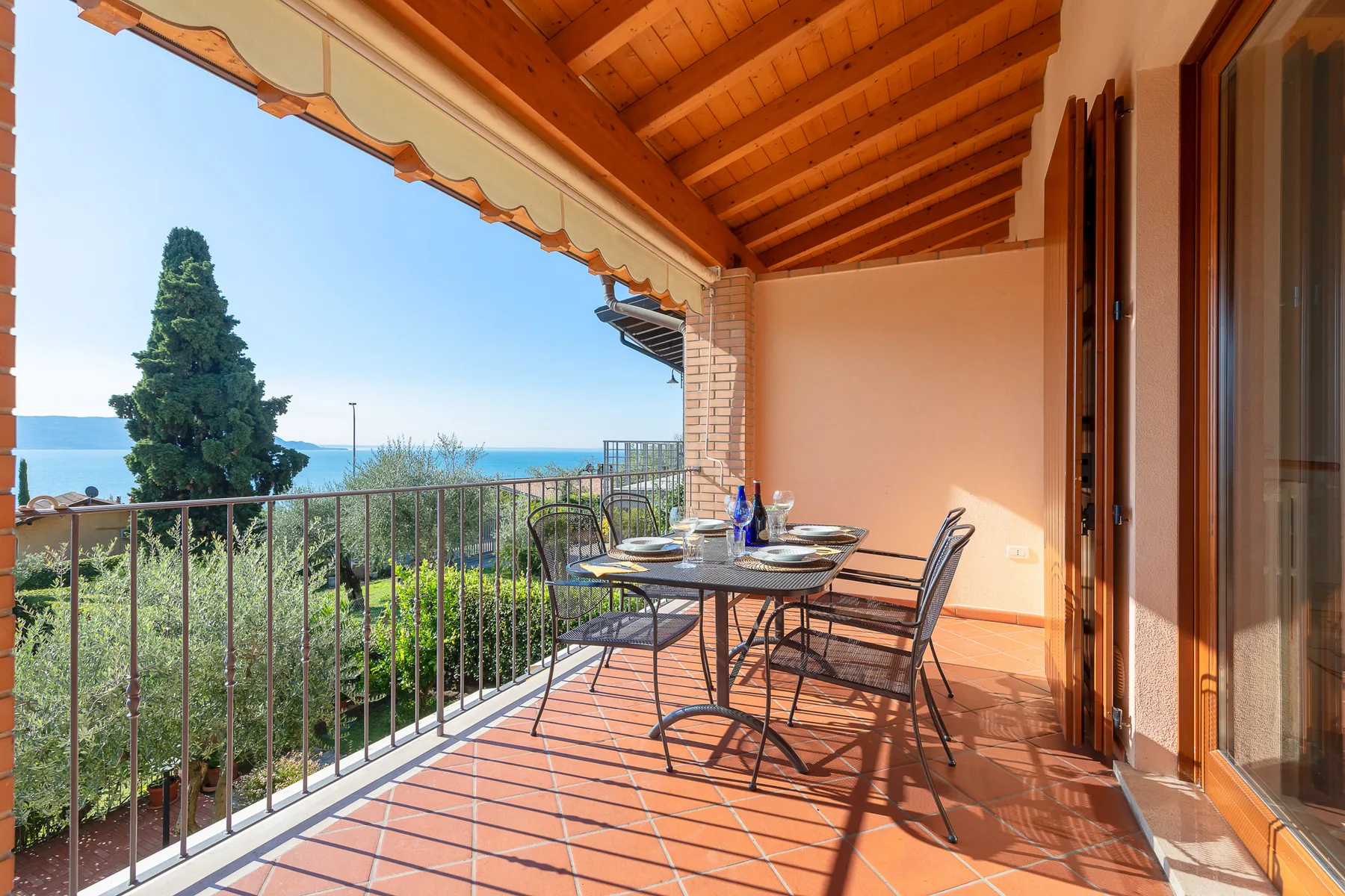 Una terraza cubierta con asientos al aire libre ofrece vistas a la vegetación y al mar.