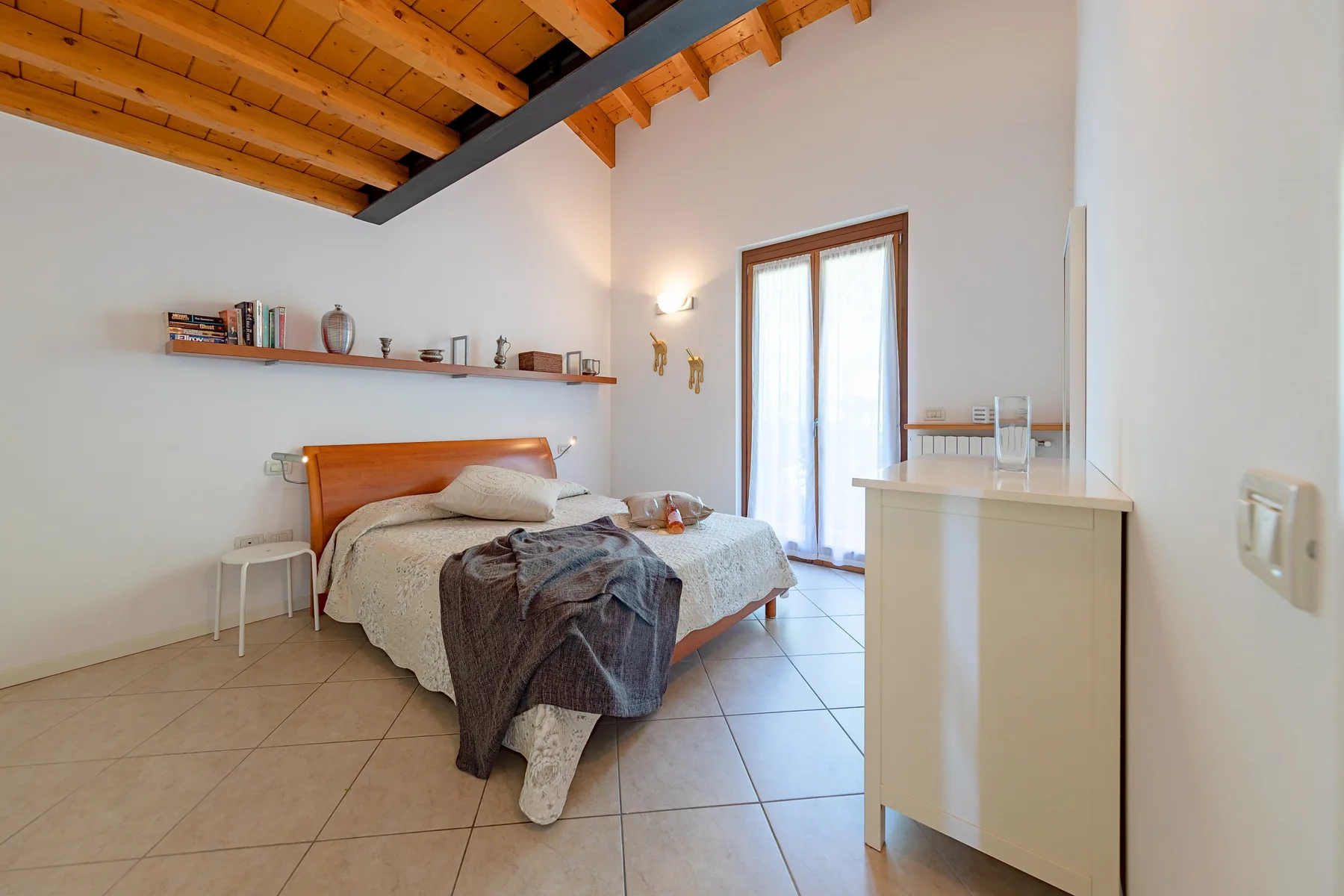 Un dormitorio con una cama, un estante de pared y un armario pequeño.