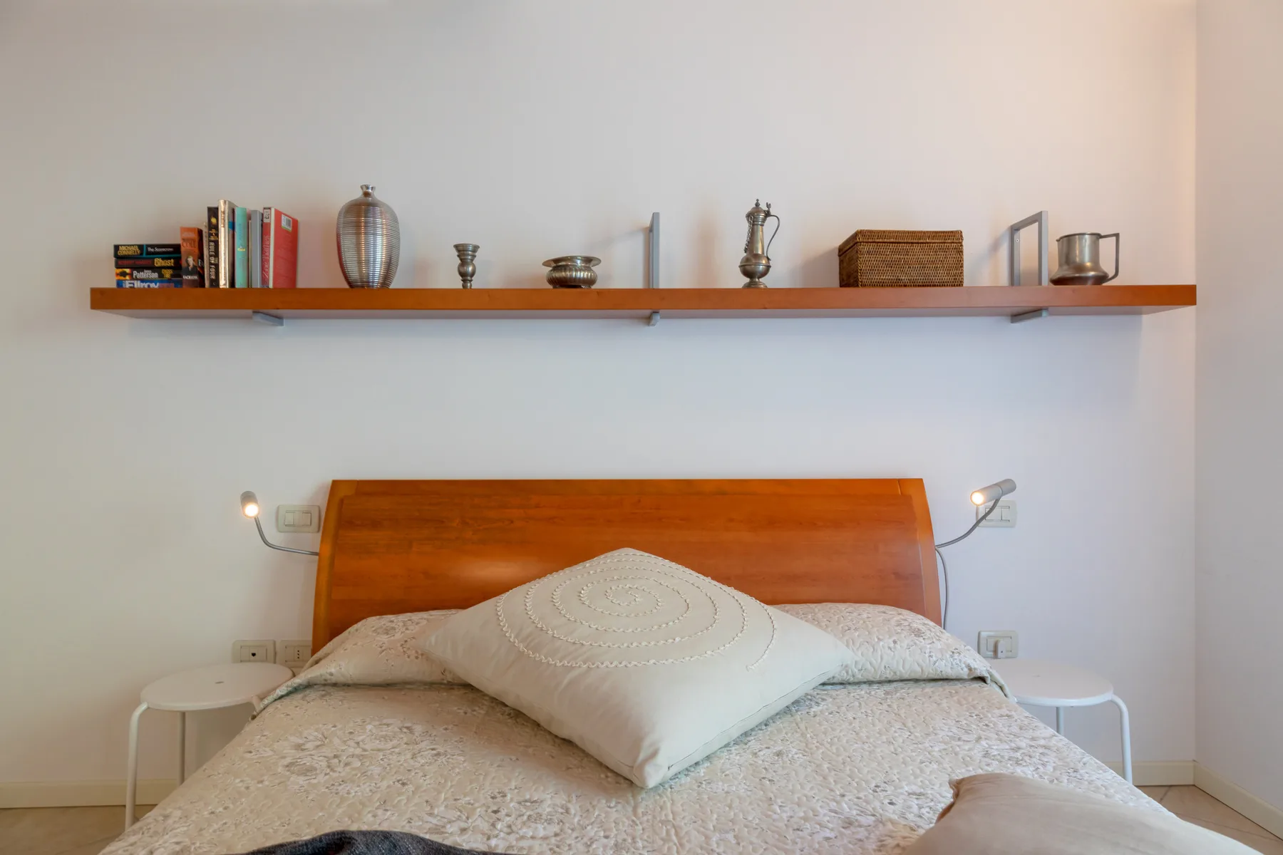 Un dormitorio con una cama debajo de una estantería larga.