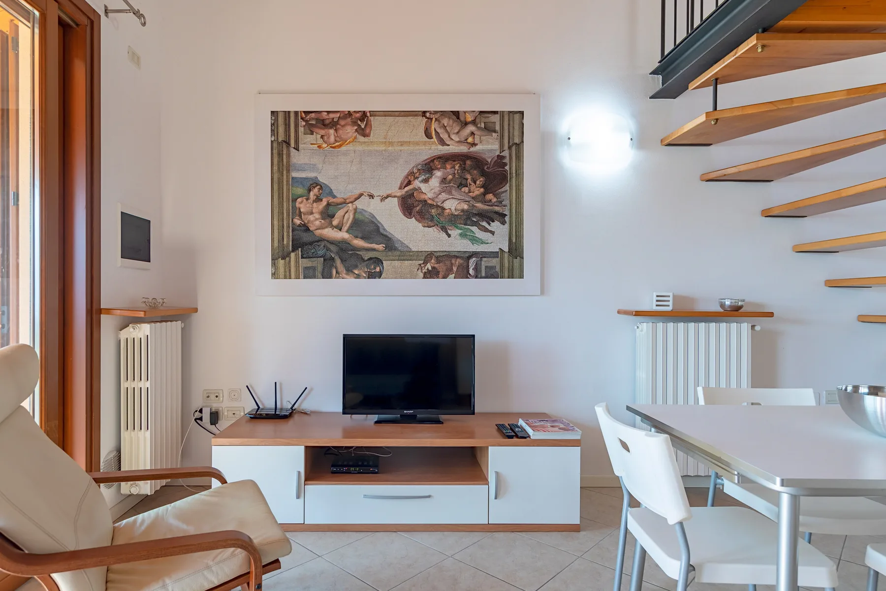 Una sala de estar y comedor con televisor, asientos y una mesa.