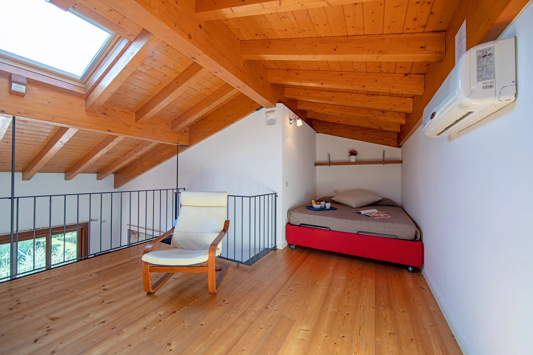 Un dormitorio en un altillo con una cama, una silla y techo inclinado de madera.