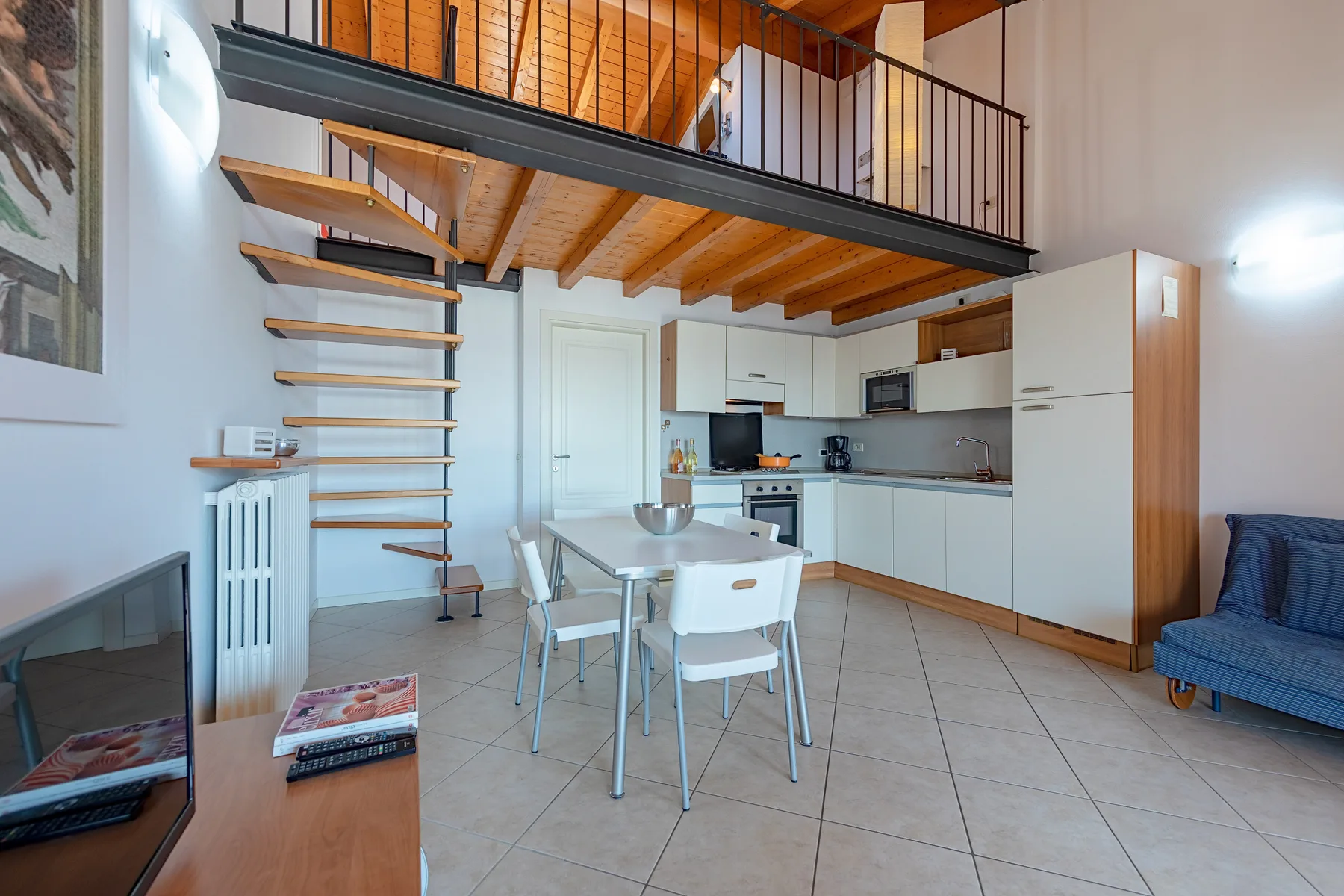 Una luminosa sala diáfana con una mesa de comedor bajo un altillo de madera.