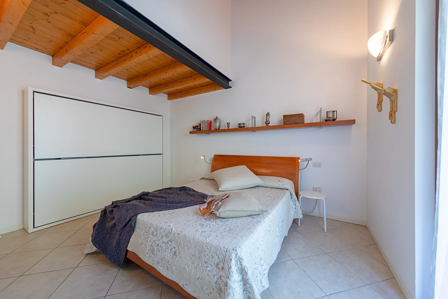 Un dormitorio con una cama bajo vigas de madera expuestas.