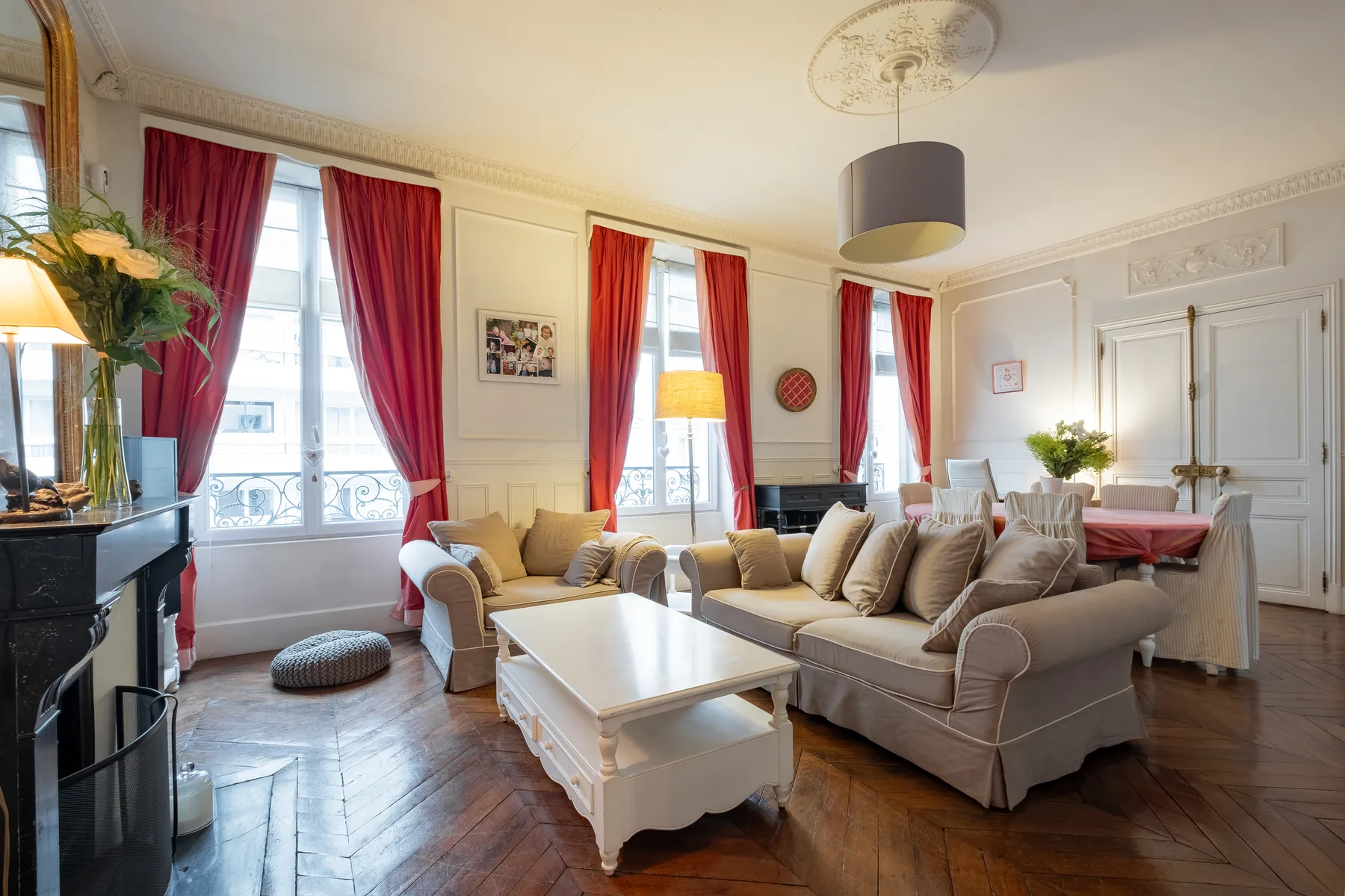 Una sala de estar luminosa con asientos alrededor de una mesa de centro blanca y ventanas altas.
