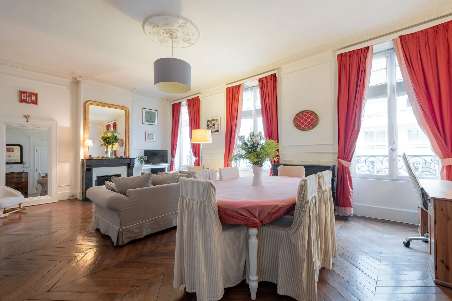Un salón comedor luminoso con cortinas rojas y una mesa puesta.