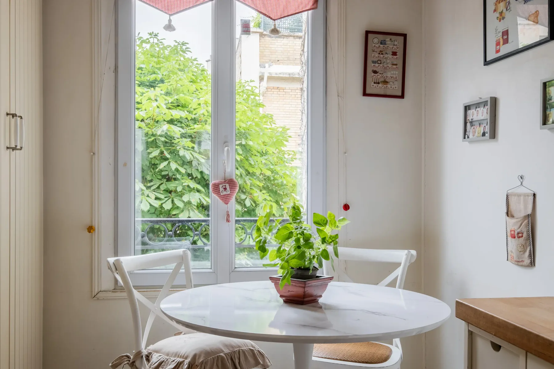 Un comedor con una mesa redonda y una planta en maceta junto a grandes ventanas.