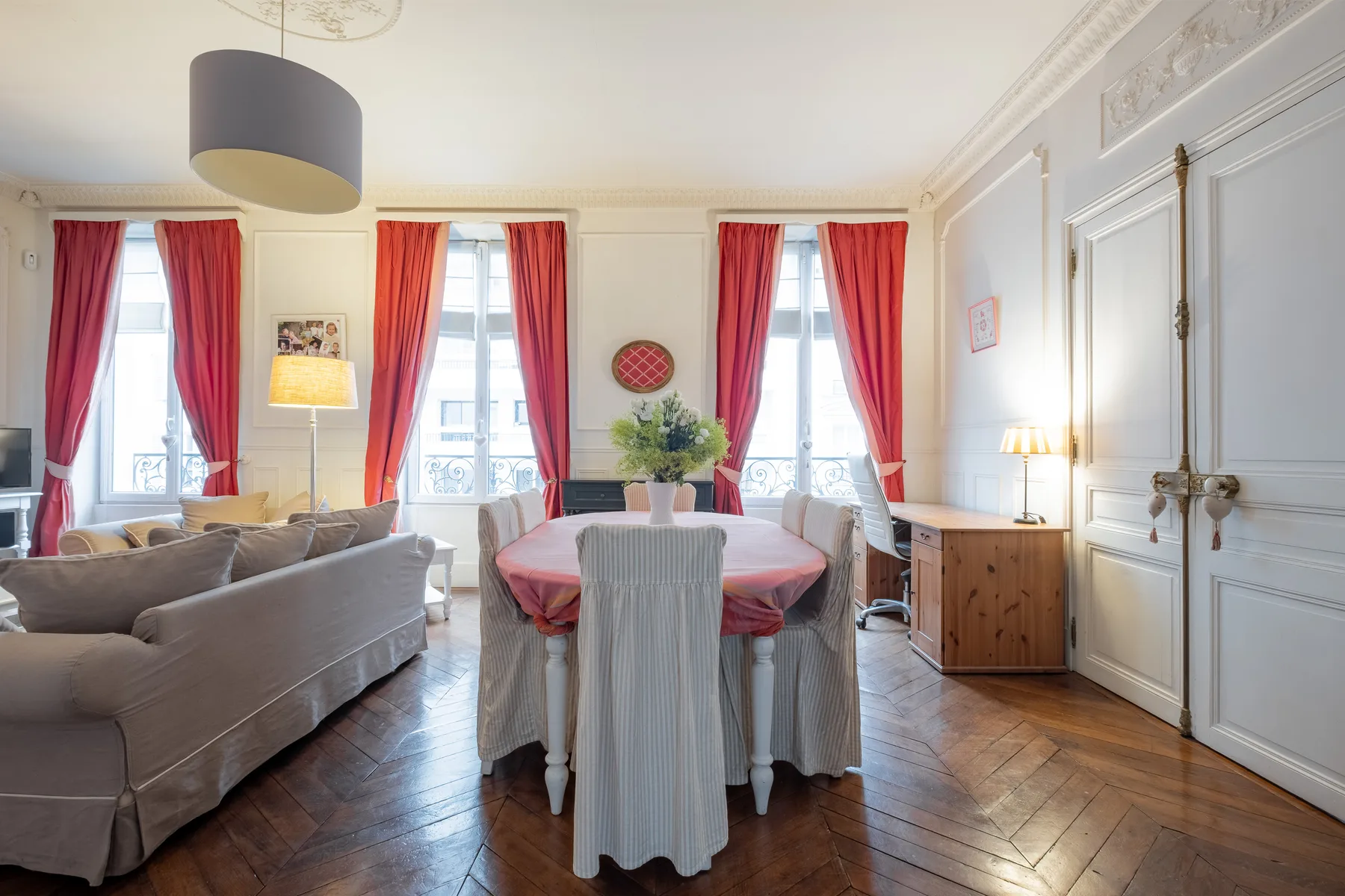 Un salón-comedor luminoso con cortinas rojas y una mesa redonda.