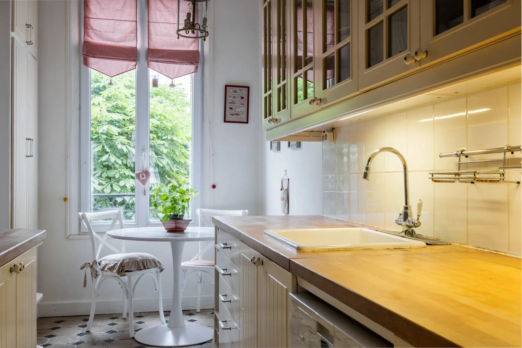Una cocina luminosa con una larga encimera de madera y una pequeña mesa junto a la ventana.
