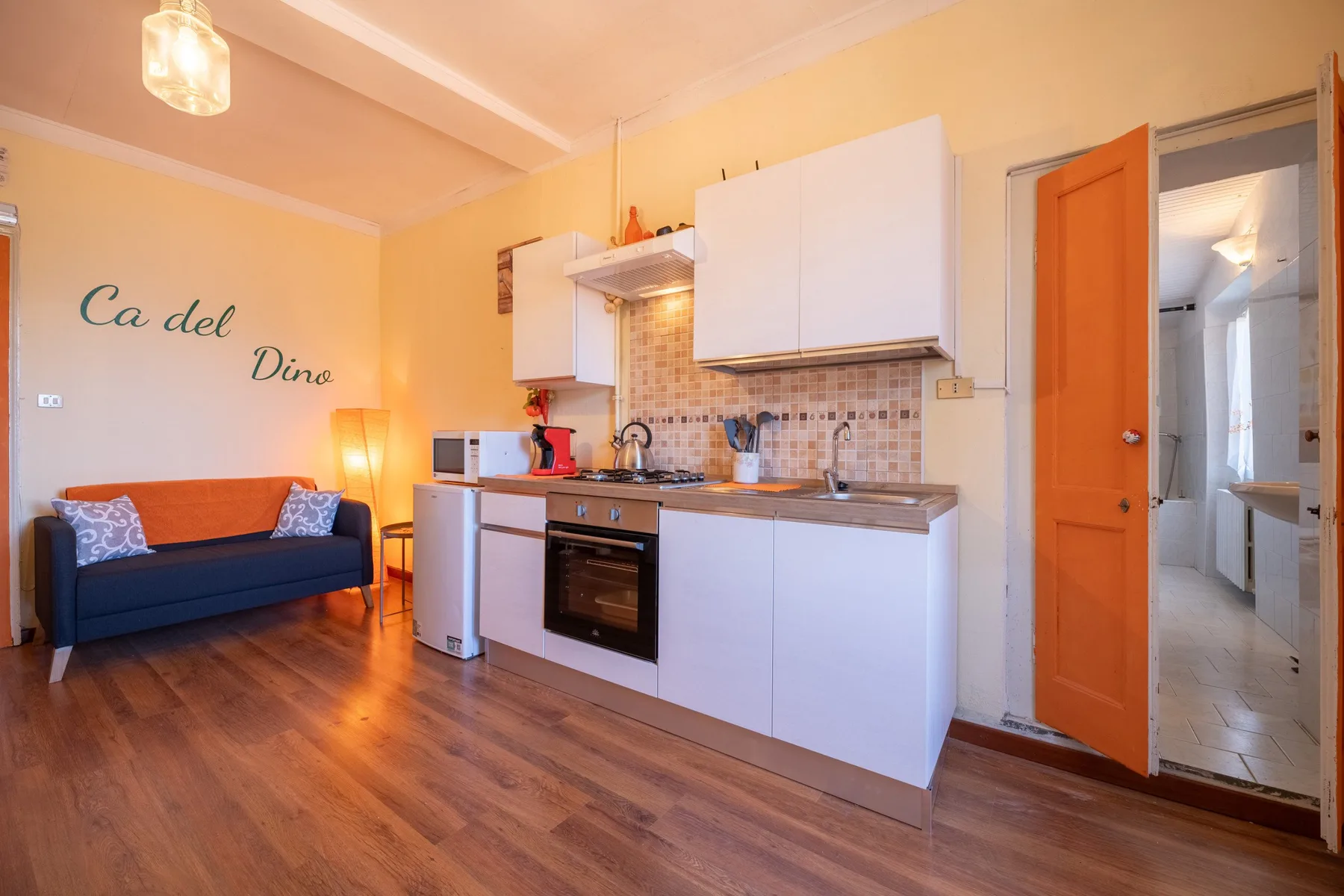 A compact kitchen and seating area with a dark couch beside the cabinets.