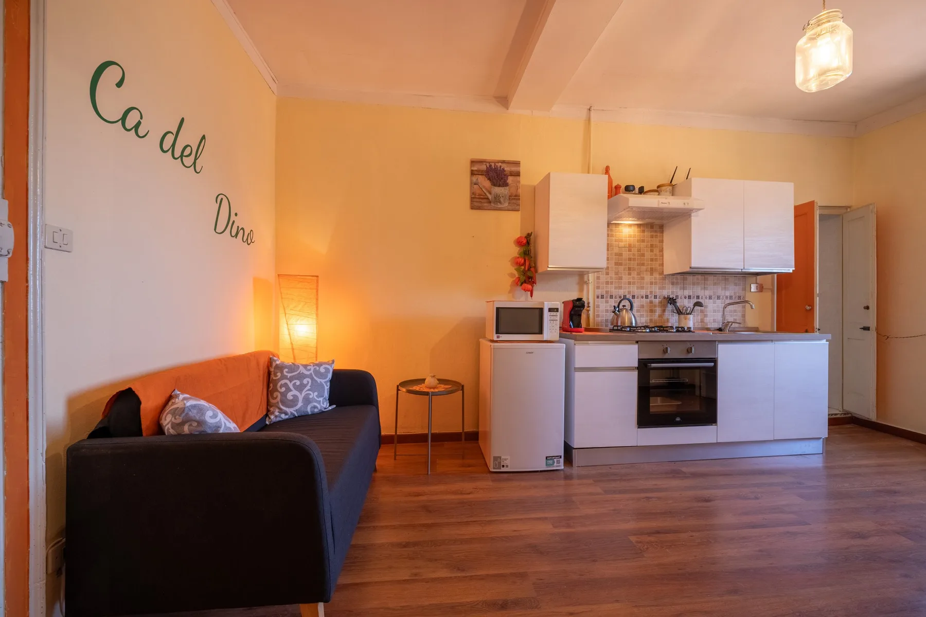 A living room opens onto a compact kitchen, with a sofa and dining table.
