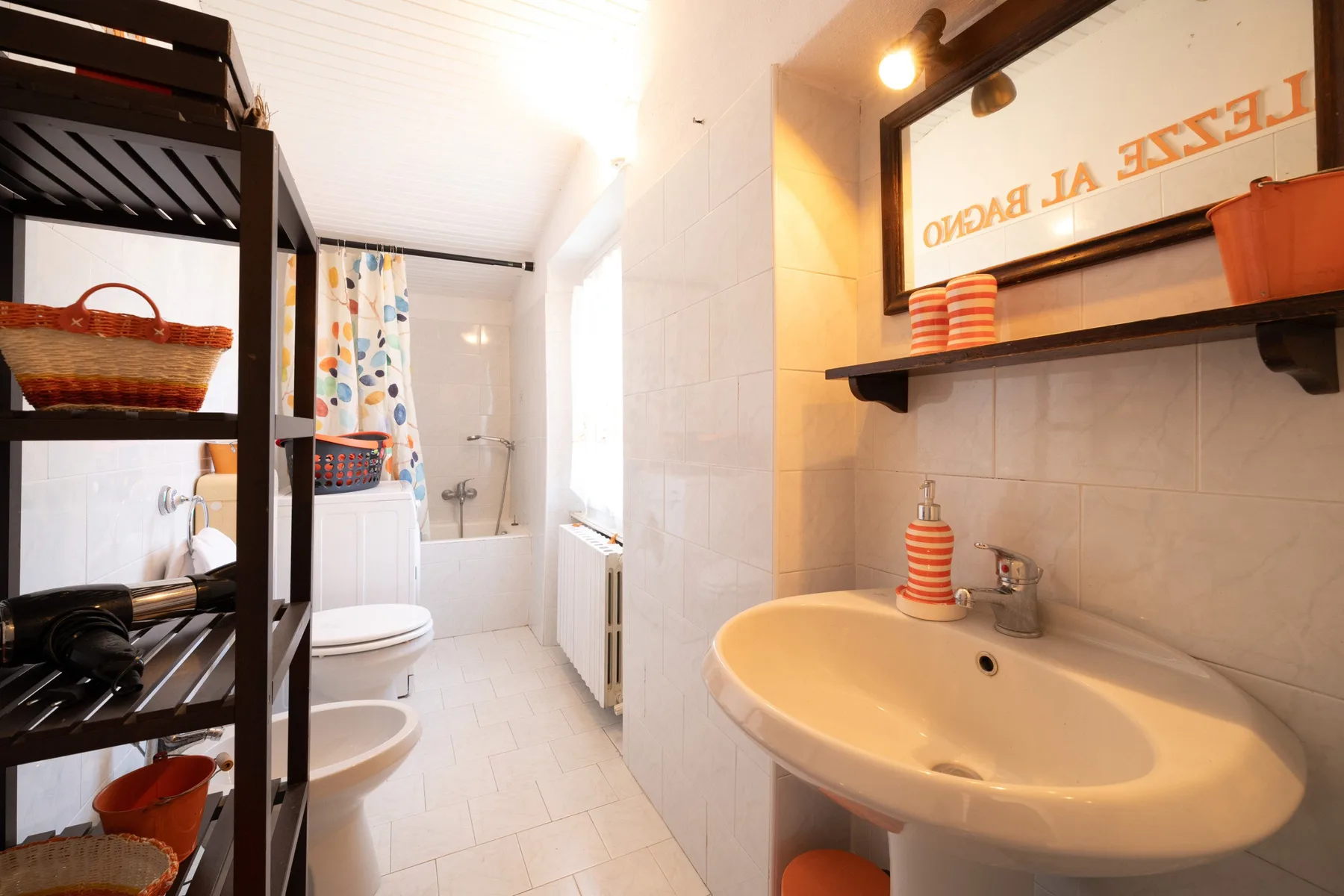 A bathroom with a sink and mirror beside a bathtub.