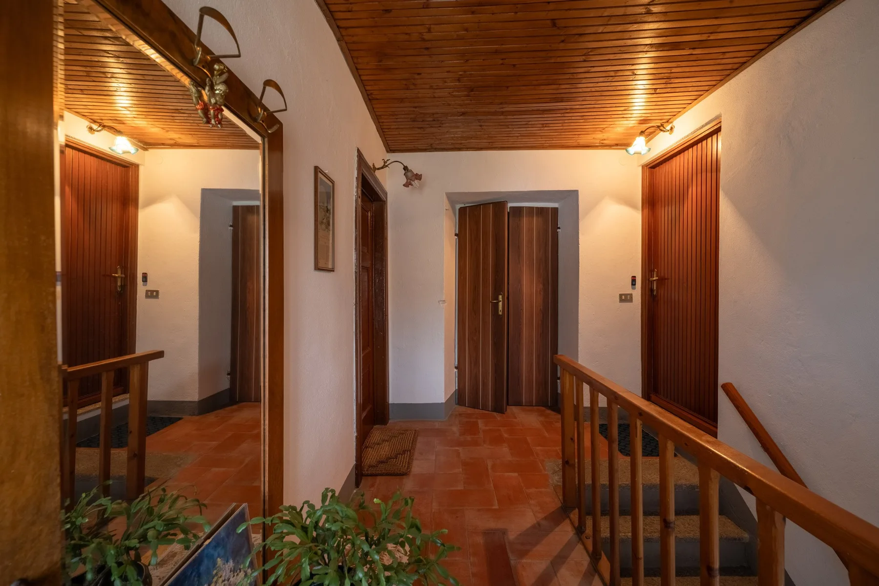 A hallway with a wooden ceiling, tiled floor, and several doors.