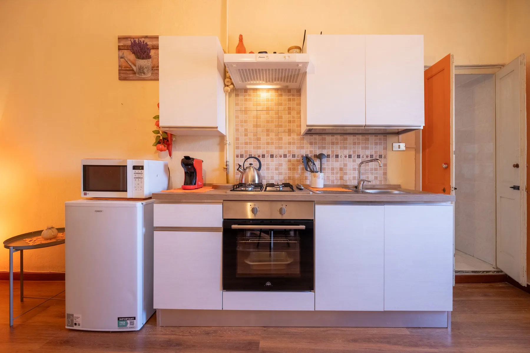 A compact kitchen with white cabinets, a tiled backsplash, and a built-in oven.