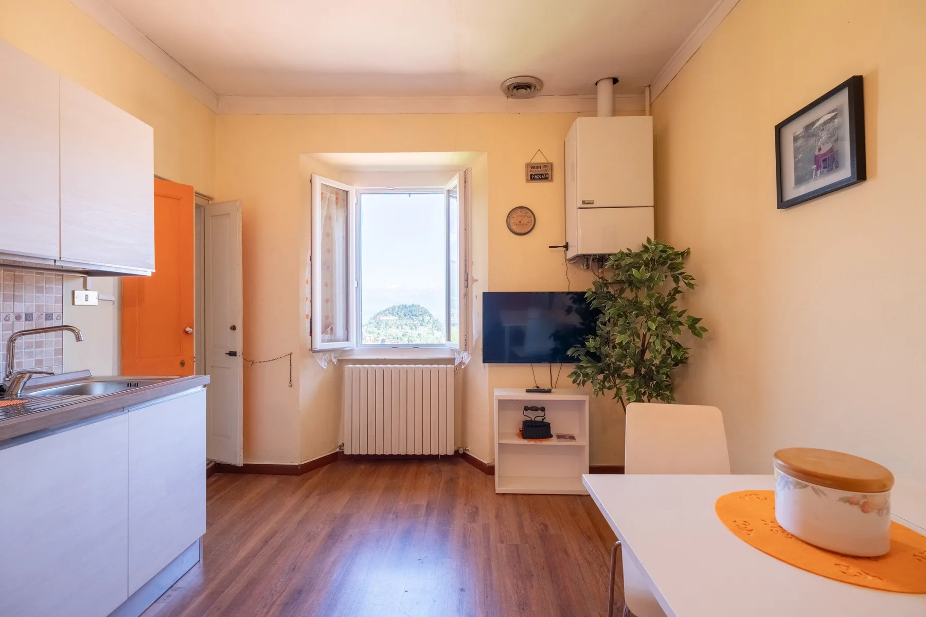 A bright kitchen and dining area with a window, television, and table.