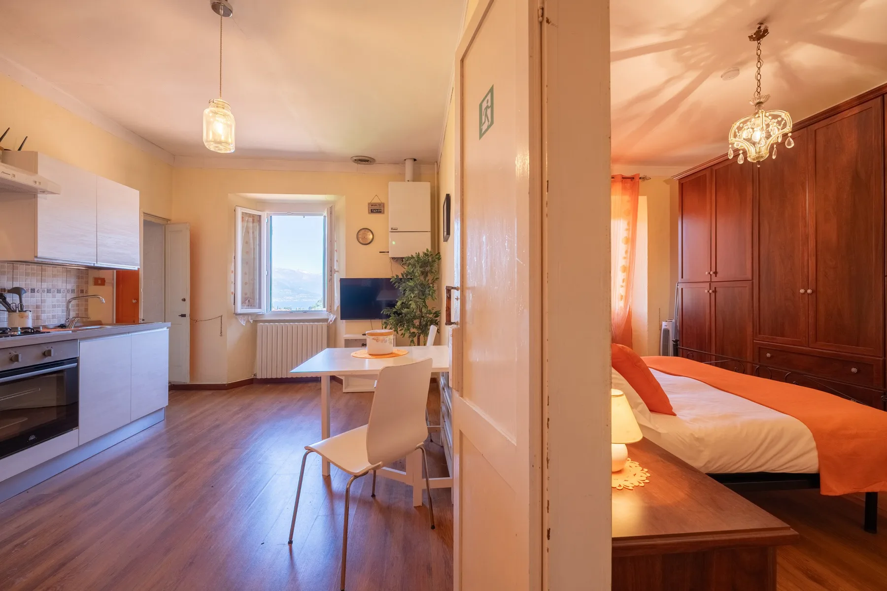 A combined kitchen and dining area opens onto a bedroom with a large wardrobe.