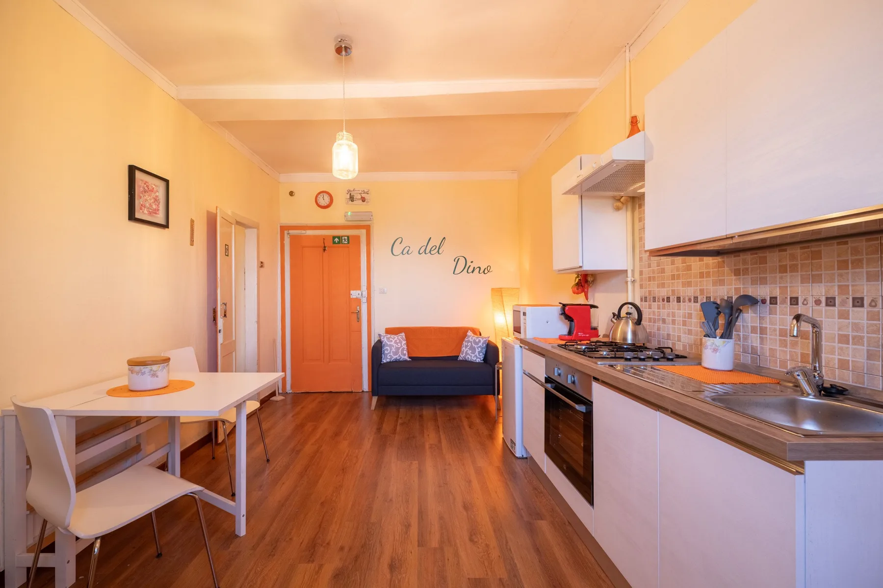 A compact kitchen and dining area with a table, seating, and wood flooring.