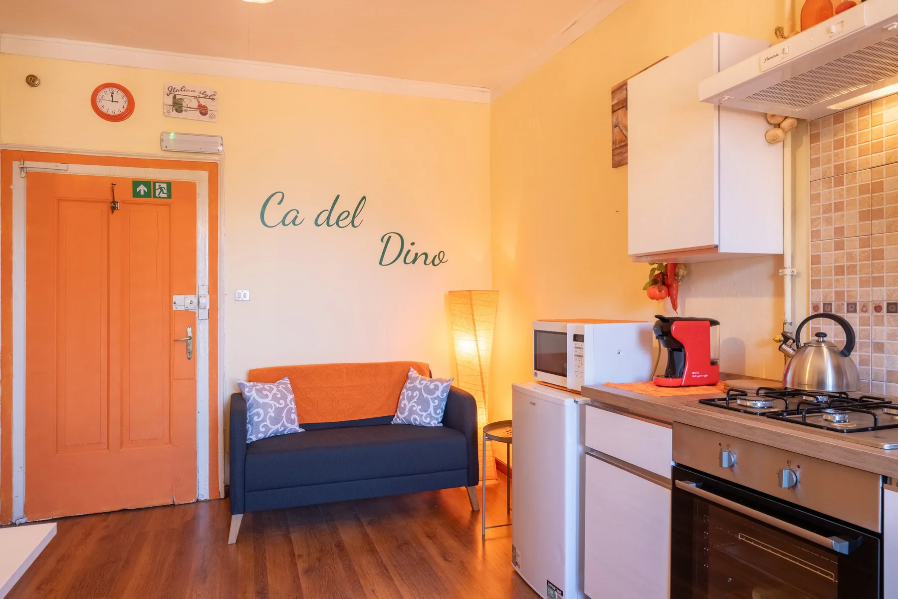 A compact living area and kitchen with a blue sofa and cooking counter.
