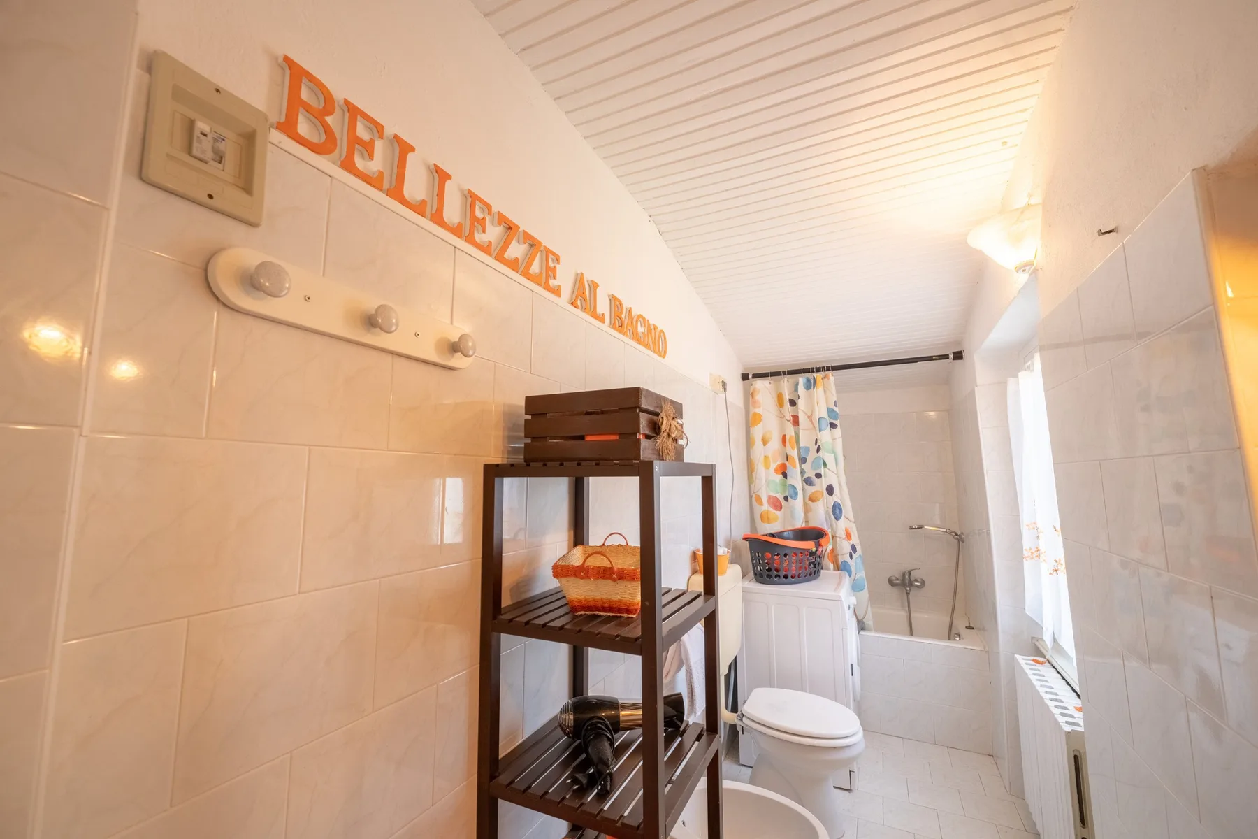 A tiled bathroom with a shower, toilet, and storage shelving.