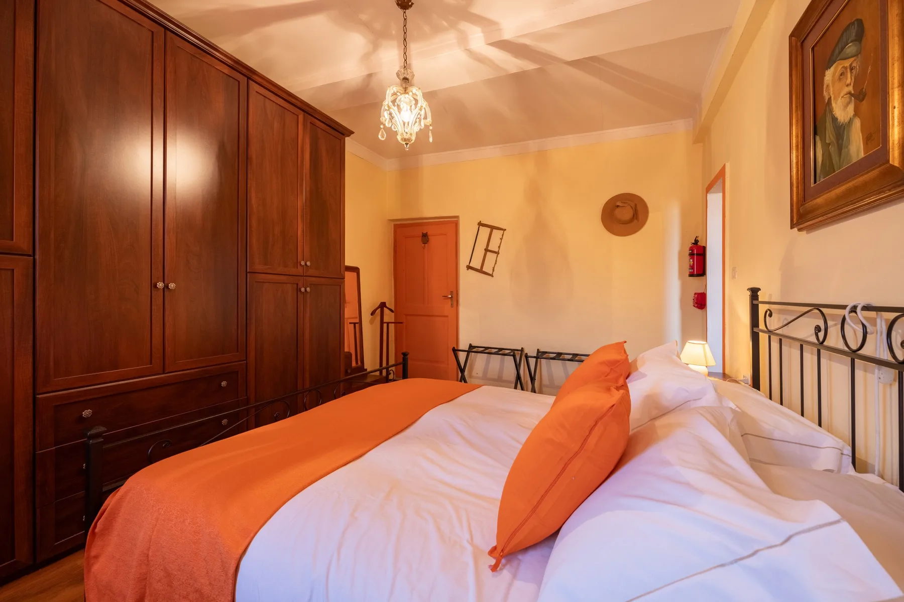 A bedroom with a large bed, orange bedding, and dark wooden wardrobes.
