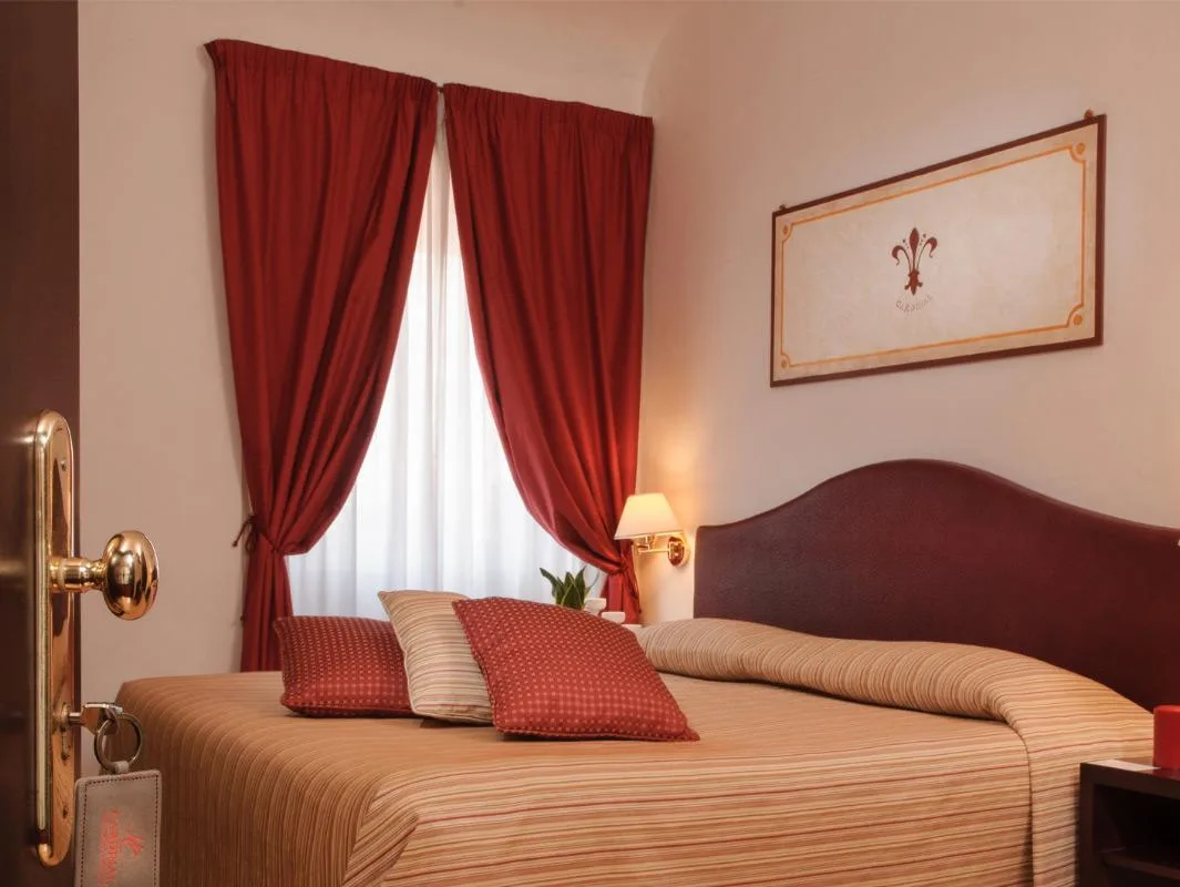 Habitación con cama doble y cortinas rojas.