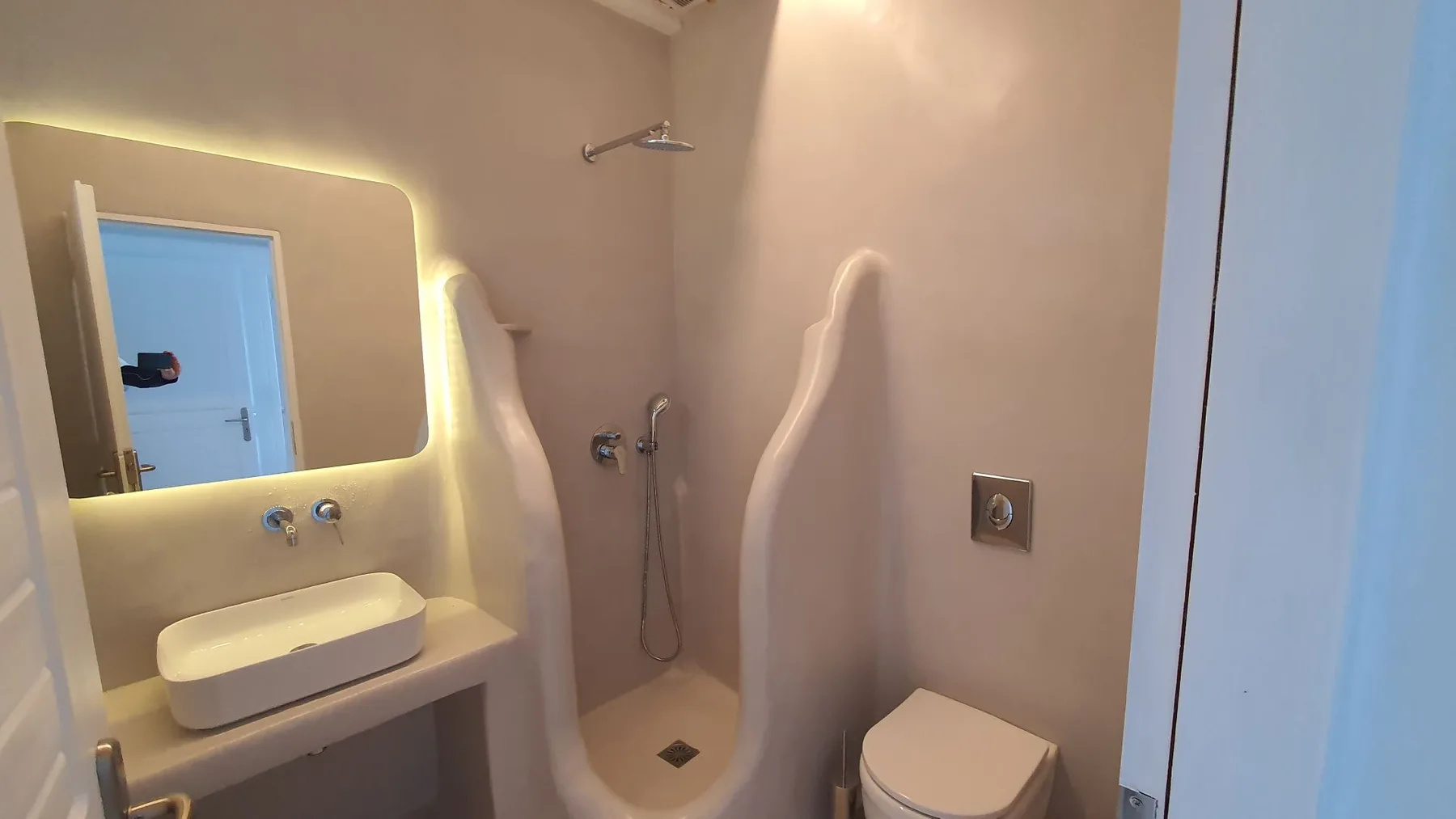 A bathroom with a sink, mirror, shower, and toilet.