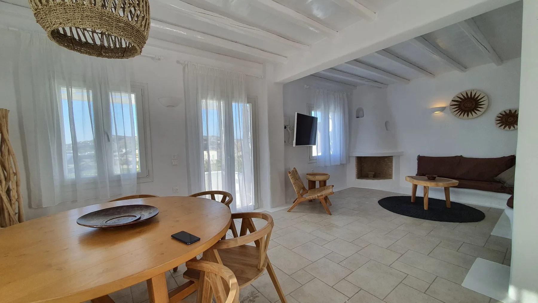 A bright living and dining area with a wooden table and seating.