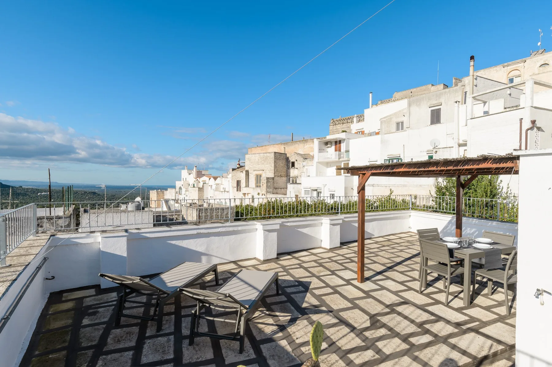 A rooftop terrace with outdoor seating and a wooden pergola overlooks the surrounding buildings.