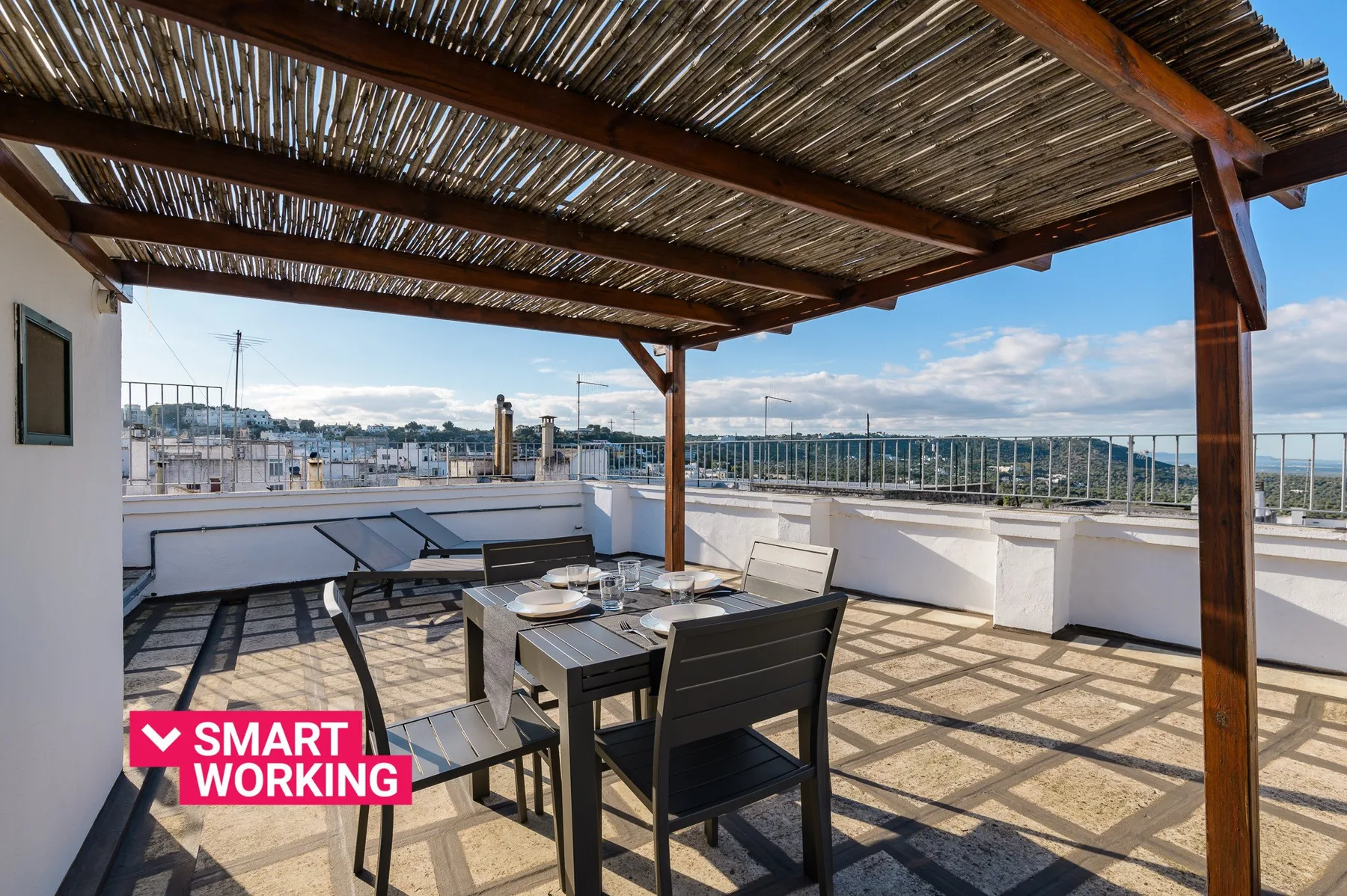 A rooftop terrace has outdoor seating beneath a slatted wooden pergola.