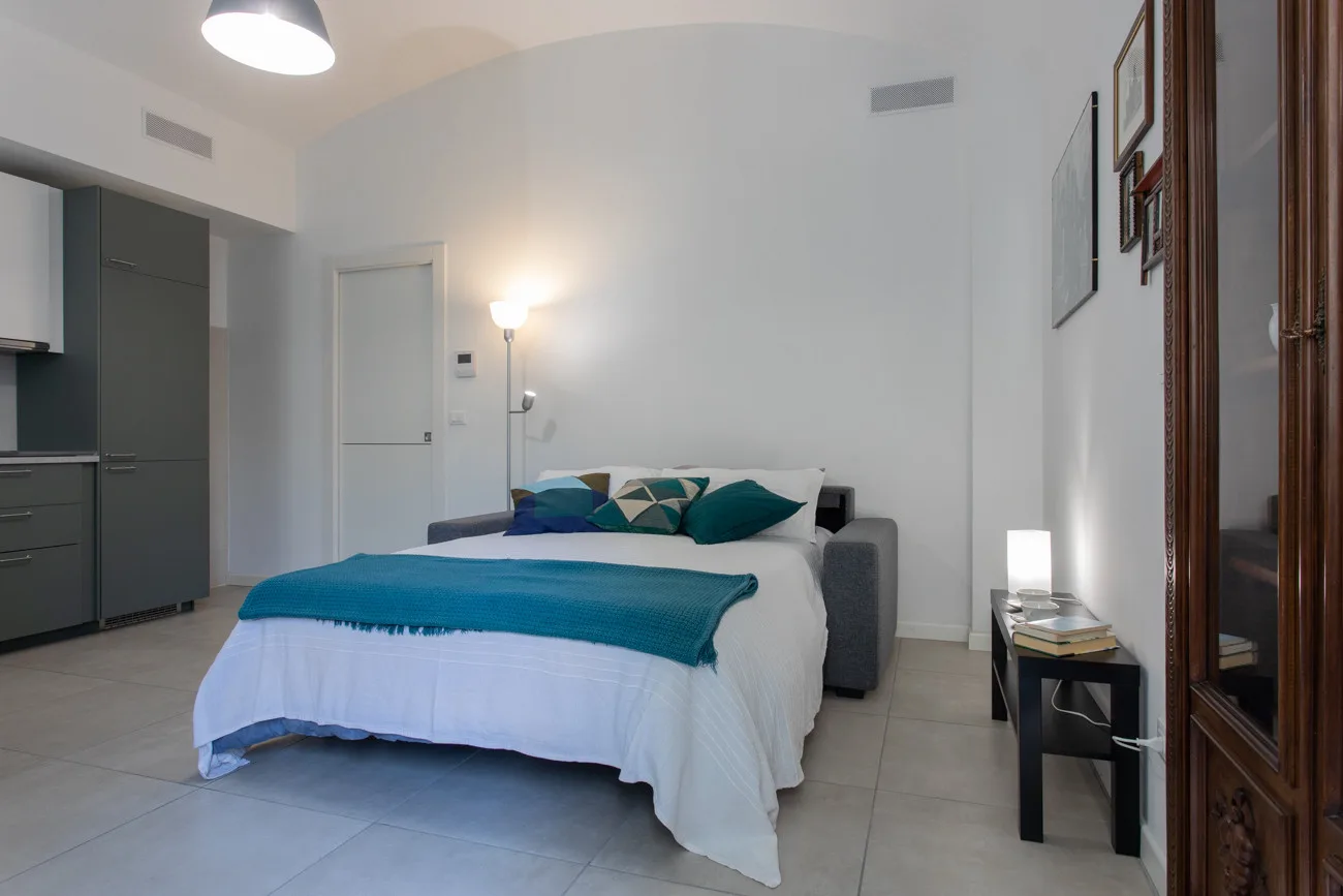 Un dormitorio con una cama vestida con ropa de cama blanca y verde azulado.
