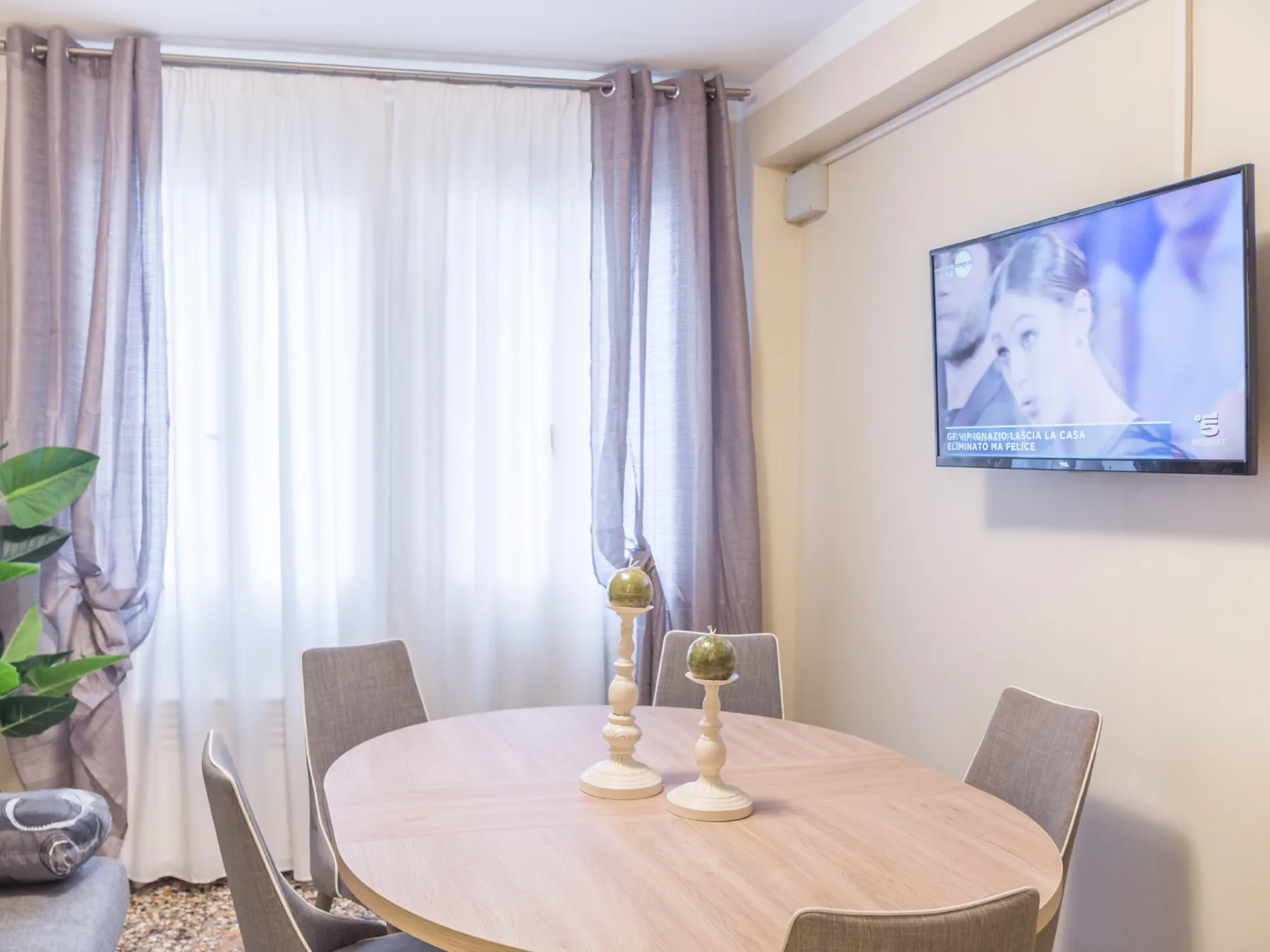 Un comedor con una mesa redonda y sillas junto a una ventana con cortinas.
