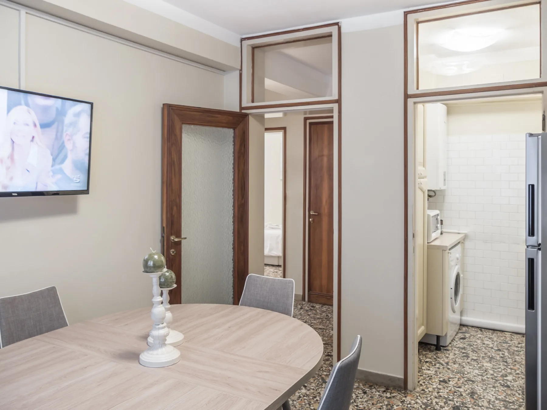 Comedor con una mesa y sillas junto a una puerta abierta hacia la cocina.