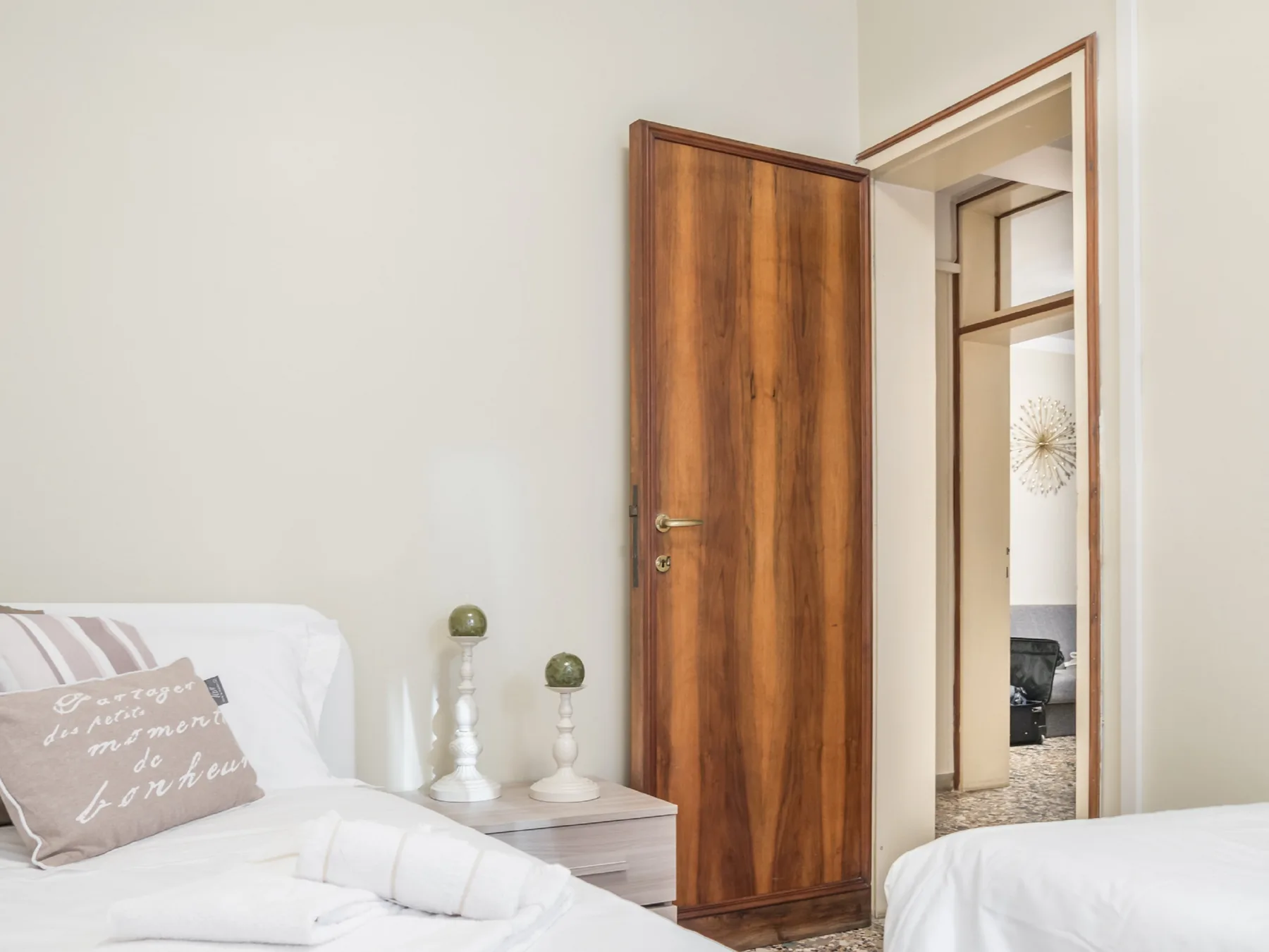 Un dormitorio con camas ordenadas y una puerta de madera abierta.