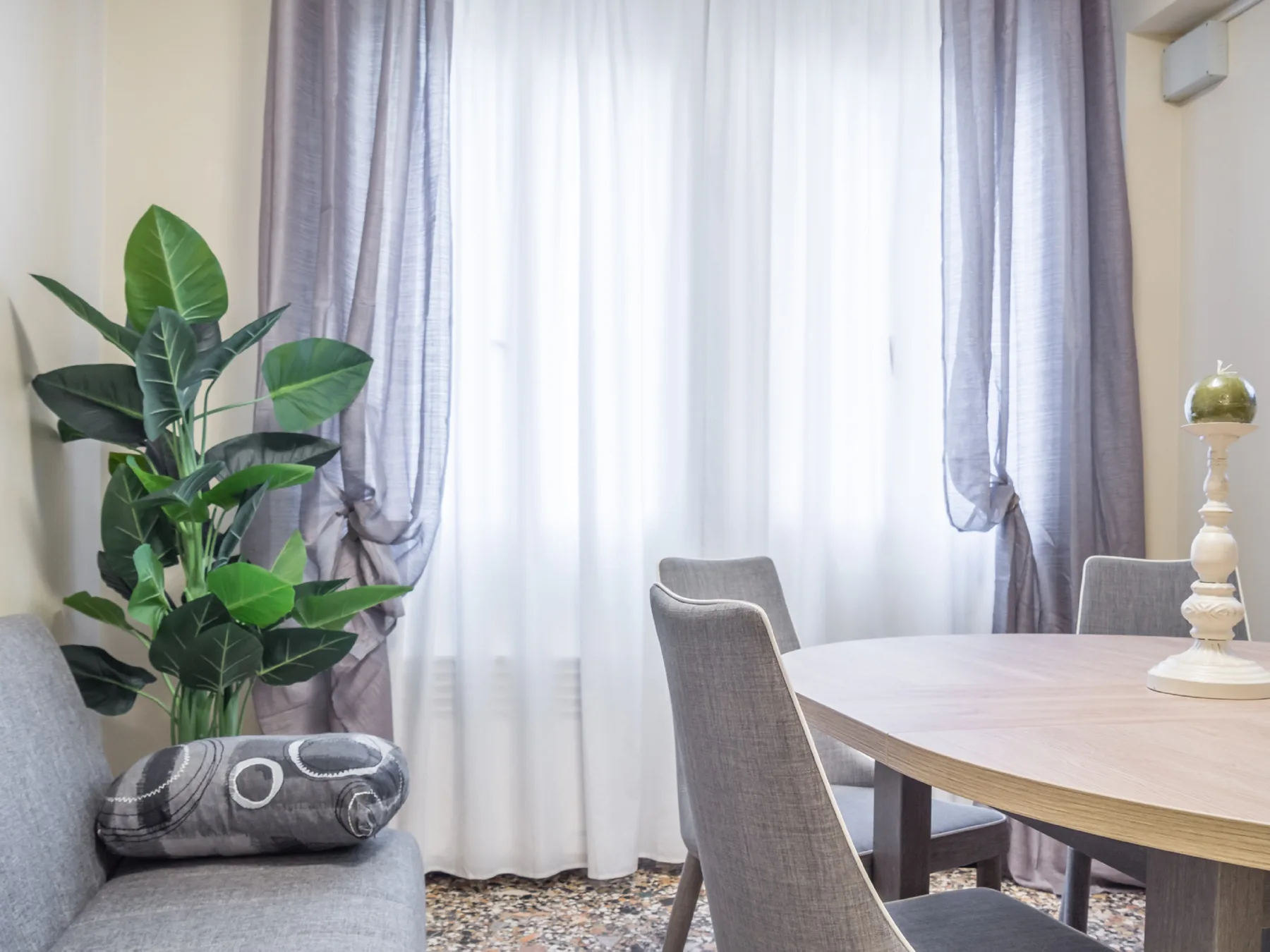 Comedor con mesa y sillas junto a una ventana grande con cortinas.