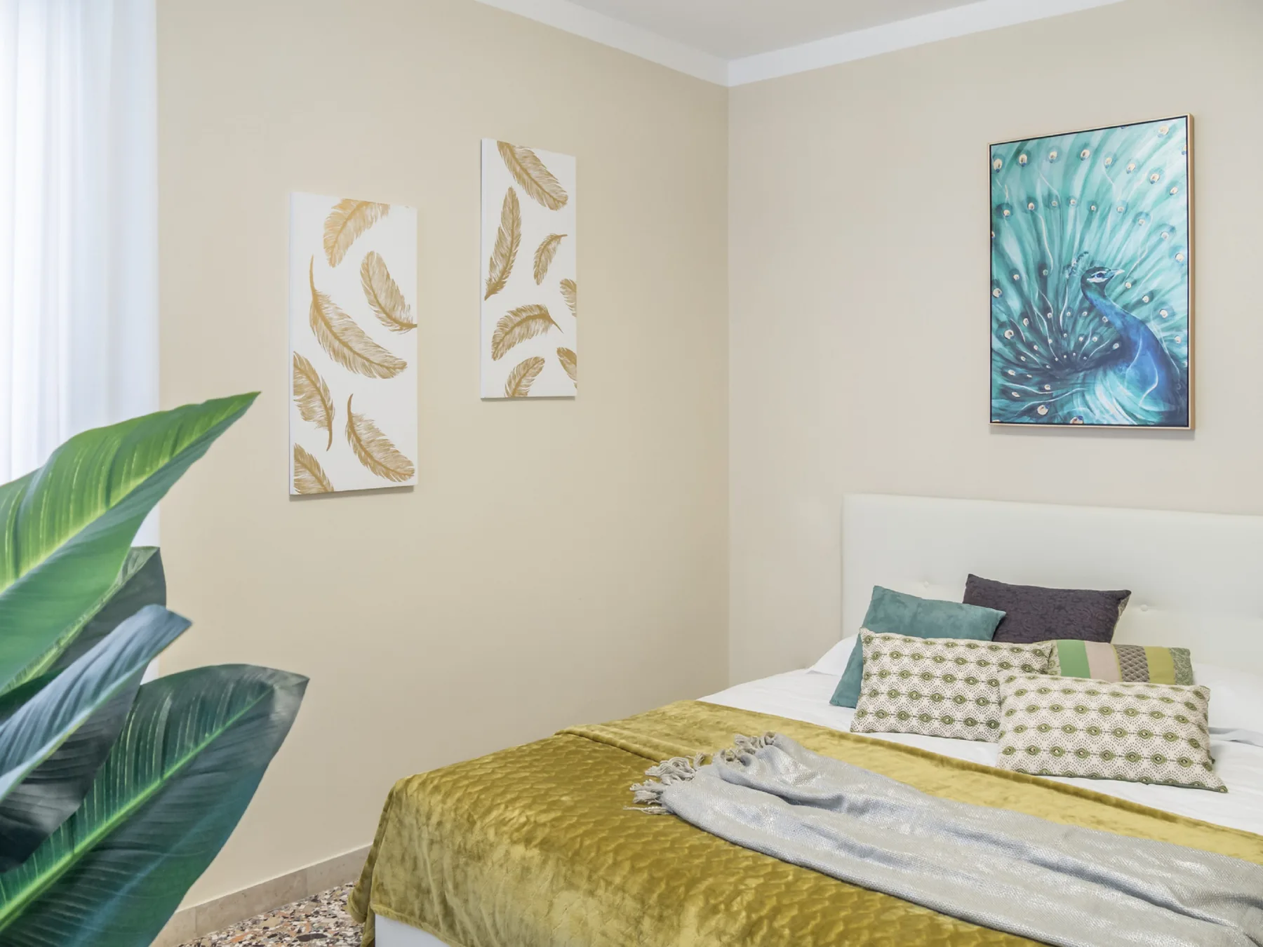 Un dormitorio con una cama cubierta con ropa de cama dorada y arte botánico en la pared.