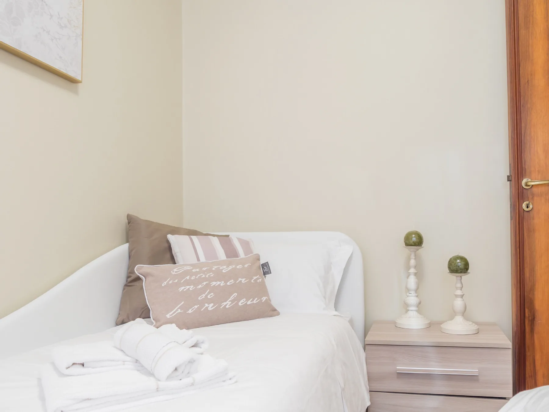 Un dormitorio con una cama bien arreglada y una mesita de noche de madera.