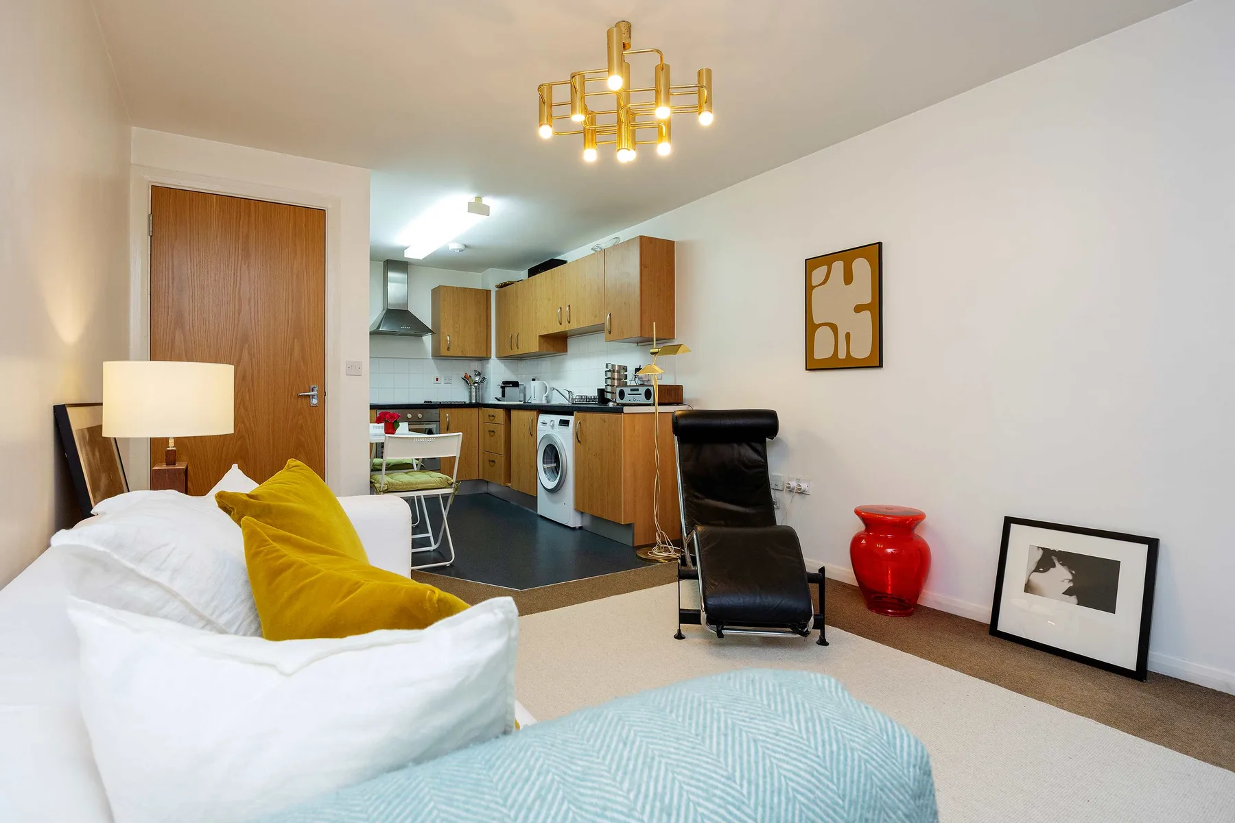 A combined living and kitchen area with seating, cabinets, and a dining table.