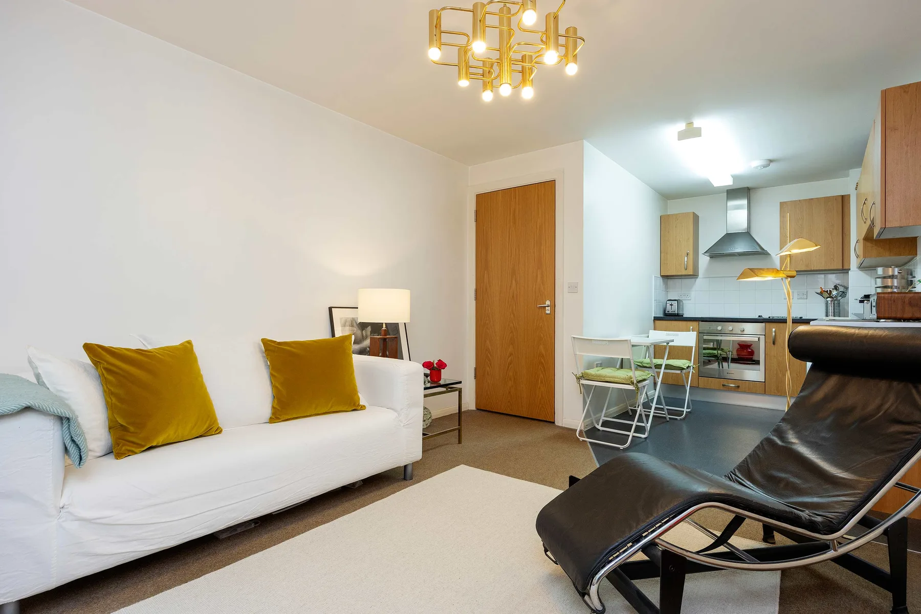 A living room with white seating and a dining area beside the kitchen.