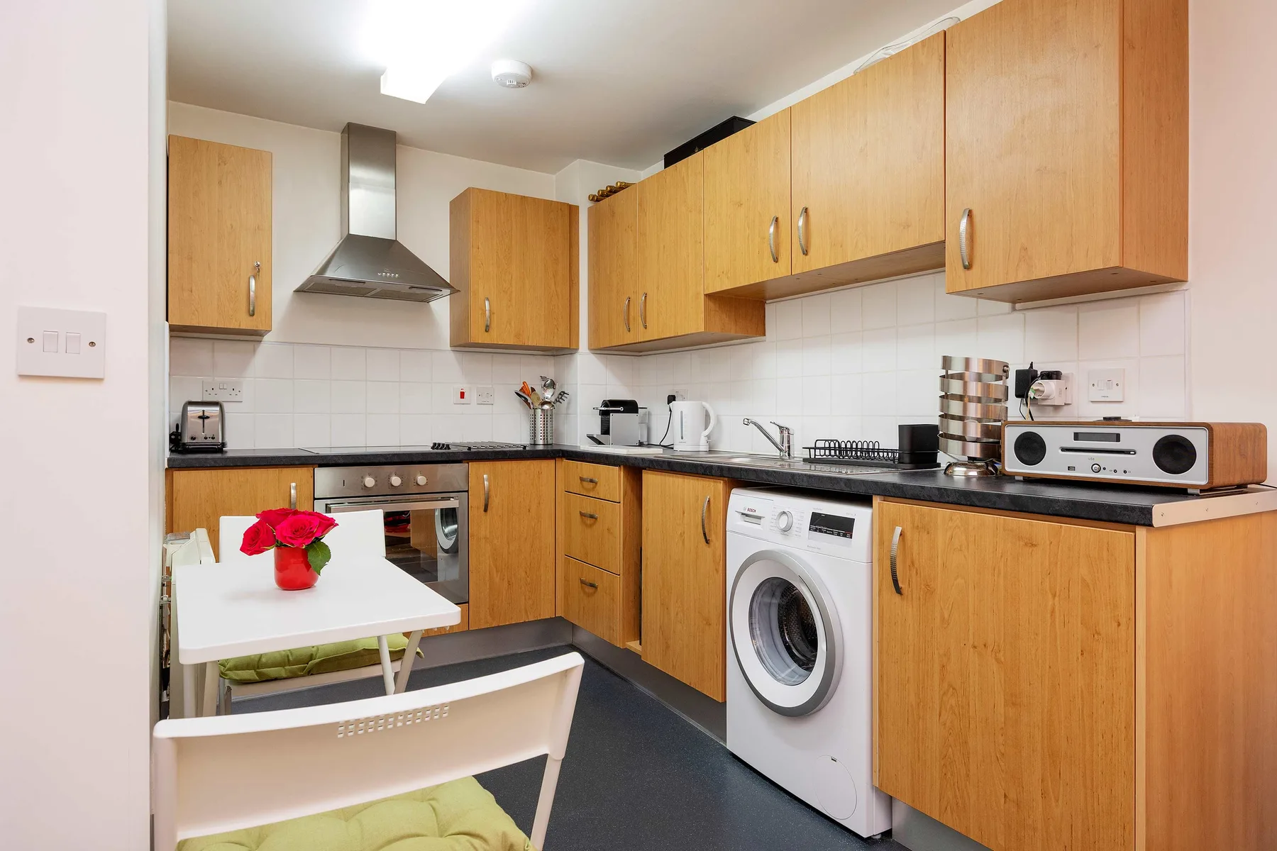 A compact kitchen with wooden cabinets, a countertop, and a washing machine.