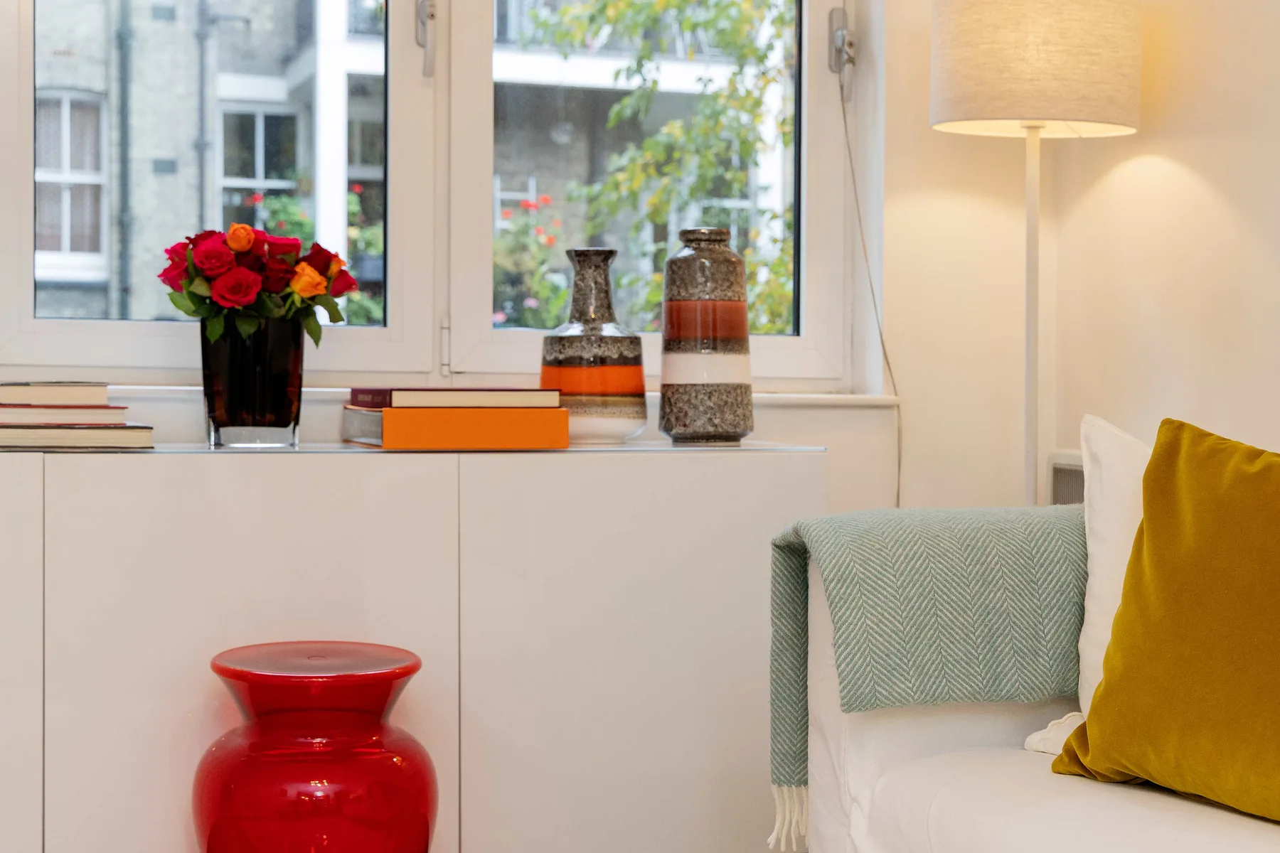 A bright living room with a window, colorful flowers, and seating.