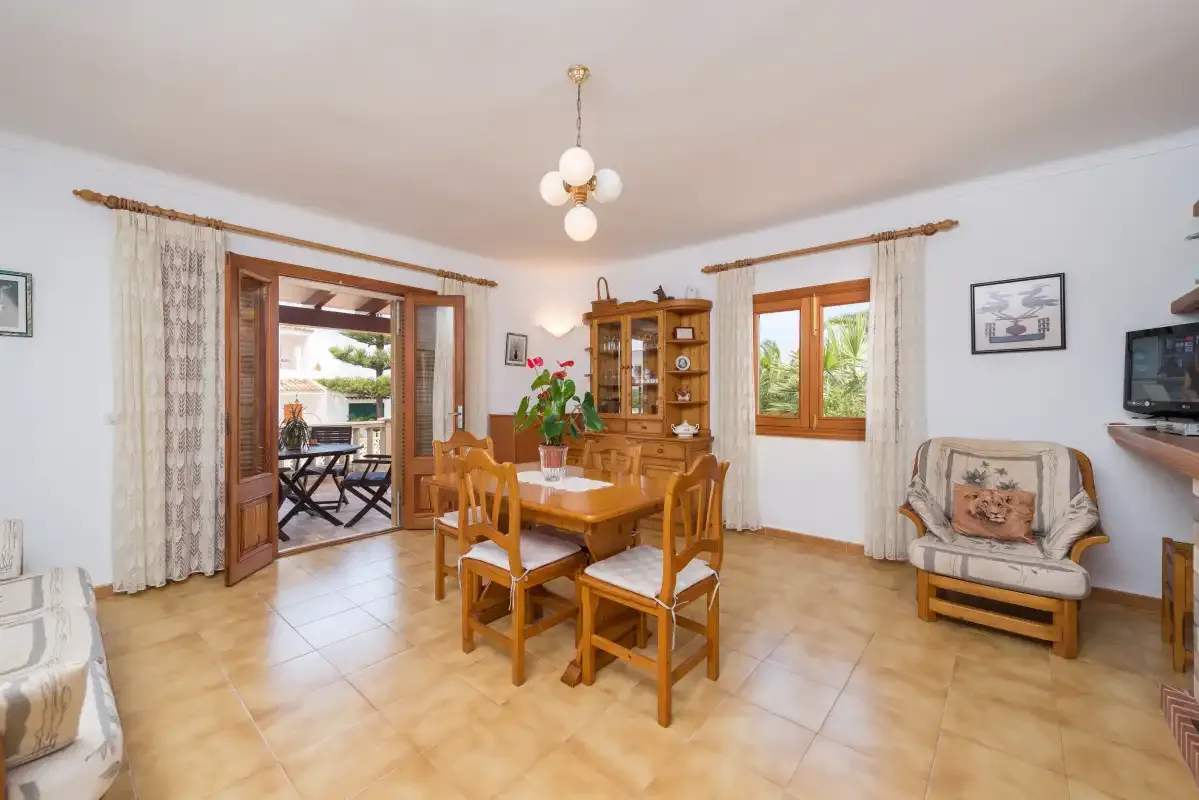 Comedor con una mesa y sillas de madera junto a una puerta abierta.