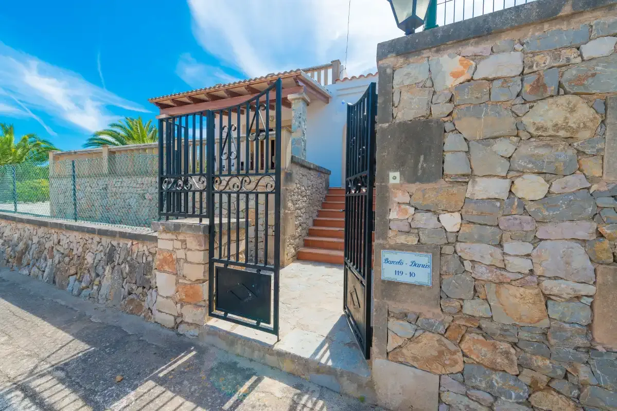 Una entrada de piedra con una puerta metálica negra abierta y escalones hacia el interior.