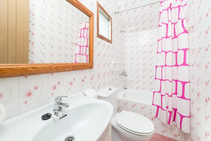 Un baño con bañera, lavabo y cortina de ducha rosa brillante.