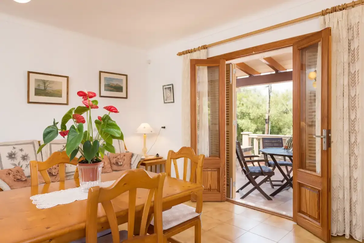 Un comedor con asientos de madera da a un patio.