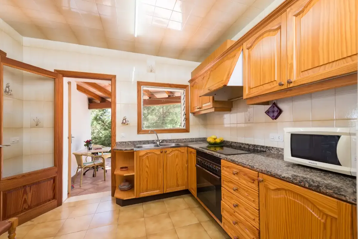 Una cocina con armarios de madera, encimeras de azulejos y un microondas.