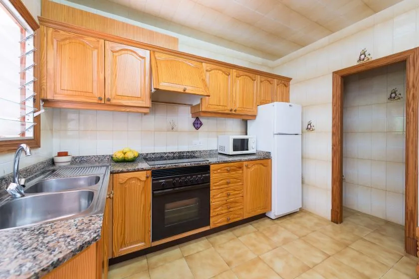 Una cocina con gabinetes de madera, una estufa y un refrigerador.