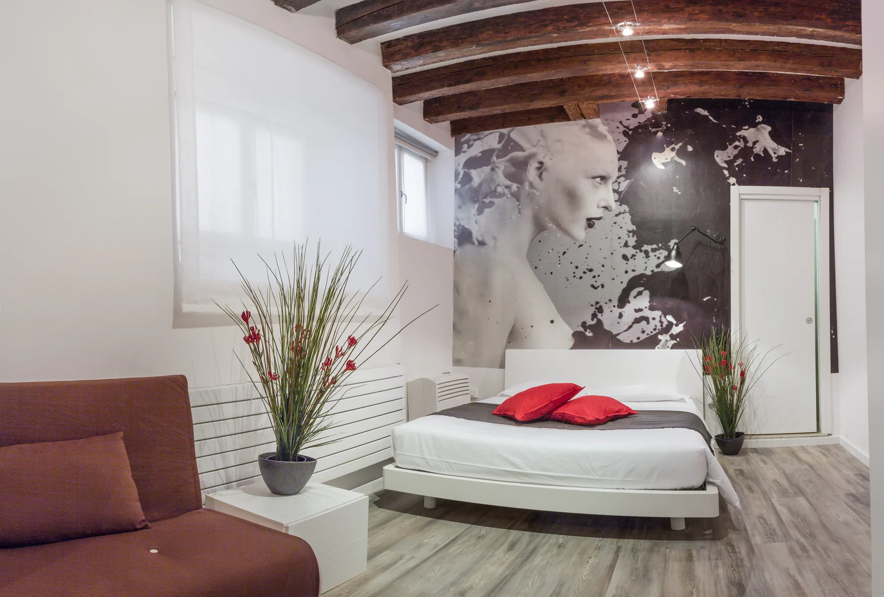 Un dormitorio con una cama baja bajo un gran mural monocromático.